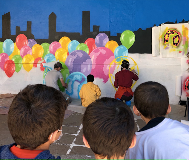 Trois élèves en premier plan en train de regarder leurs camarades réaliser la fresque - 1 
